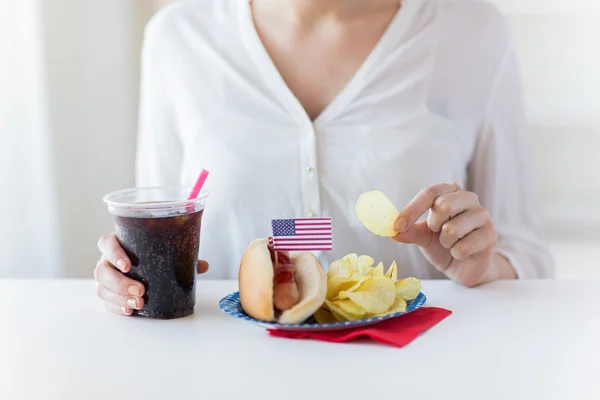 Close up van vrouw eten chips, hotdog en cola — Stockfoto