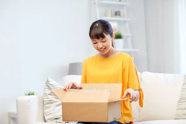 Feliz asiático jovem mulher com pacote caixa em casa — Fotografia de Stock