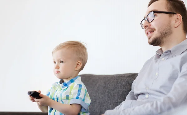 Pai e filho com controle remoto assistindo tv em casa — Fotografia de Stock