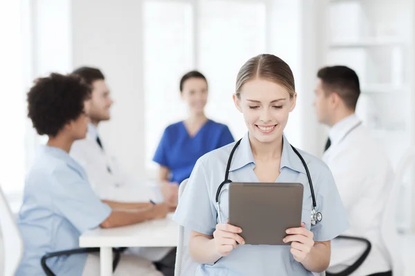 Happy doctor with tablet pc over team at clinic — Stock Photo, Image