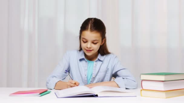 Chica de la escuela feliz con libros y bloc de notas en casa — Vídeos de Stock