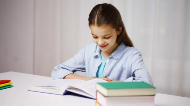 Chica de la escuela feliz lectura libro o libro de texto en casa — Vídeo de stock