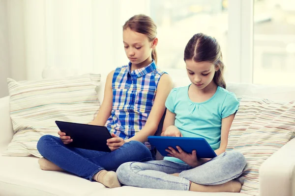 Девочки с планшетным компьютером сидят дома на диване — стоковое фото