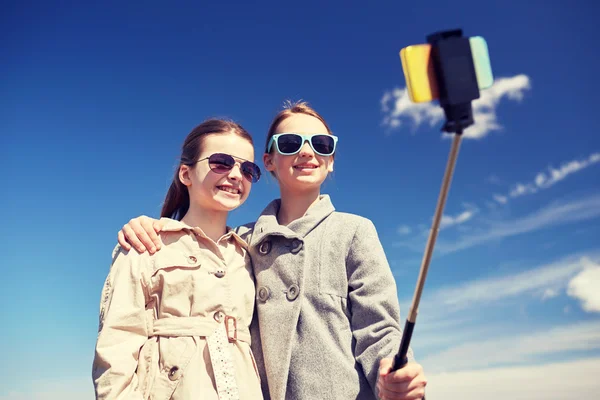 Happy girls with smartphone selfie stick — Stock Photo, Image