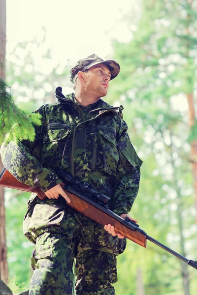 Young soldier or hunter with gun in forest — Stock Photo, Image