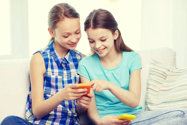 Счастливые девушки со смартфонами, сидящие на диване — стоковое фото
