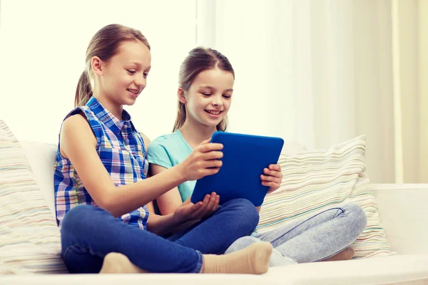 Счастливые девочки с планшетным компьютером, сидящие на диване дома — стоковое фото