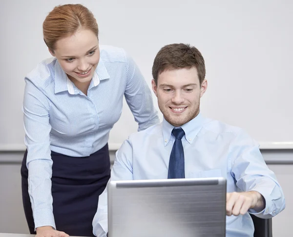 Empresários sorridentes com laptop no escritório — Fotografia de Stock