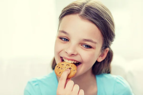 Smiling little girl eating cookie or biscuit — Stock Photo, Image