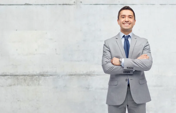 Happy businessman in suit over concrete wall — Stock Photo, Image