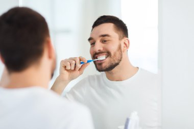man with toothbrush cleaning teeth at bathroom clipart