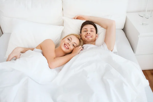 Casal feliz deitado na cama em casa — Fotografia de Stock