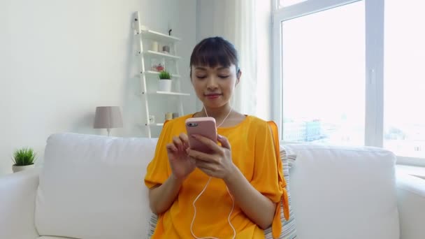 Boldog ázsiai nő smartphone és fülhallgató — Stock videók