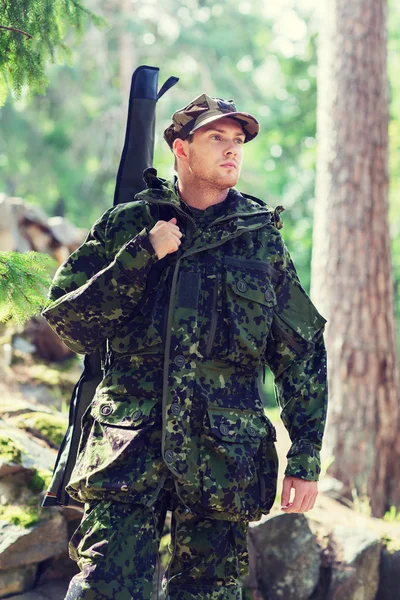 Young soldier or hunter with gun in forest — Stock Photo, Image