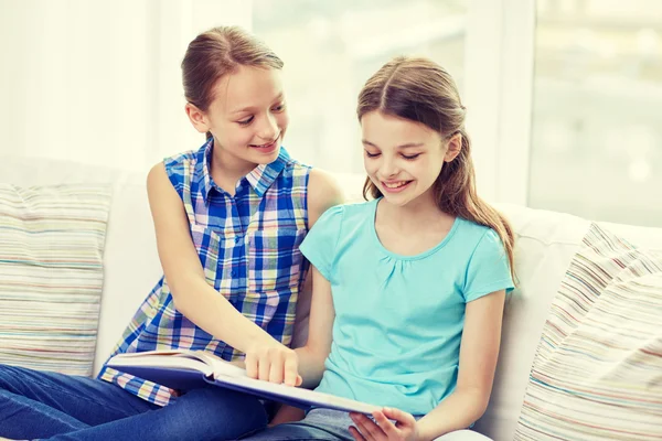 Две счастливые девочки читают книгу дома — стоковое фото