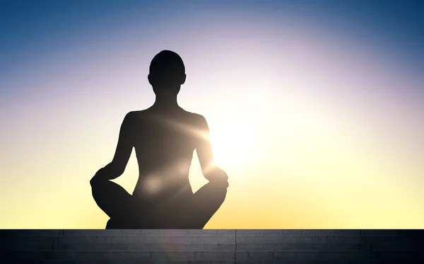 Woman meditating in yoga lotus pose over sun light — ストック写真