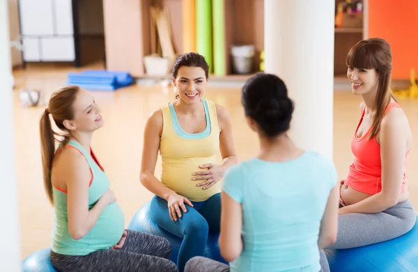 Счастливые беременные женщины сидят на мячах в спортзале — стоковое фото
