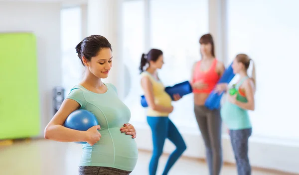 Gelukkig zwangere vrouw met bal in sportschool — Stockfoto