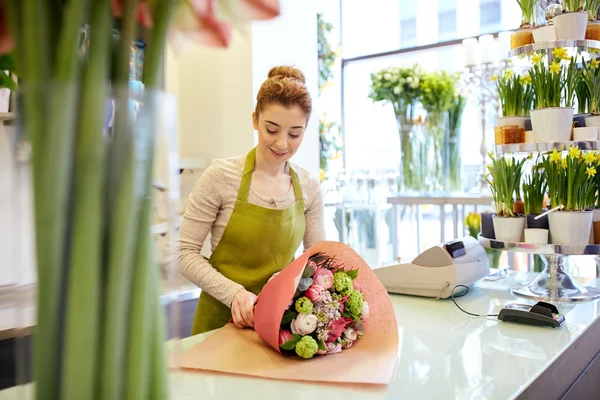 Sonriente florista mujer embalaje ramo en floristería — Foto de Stock