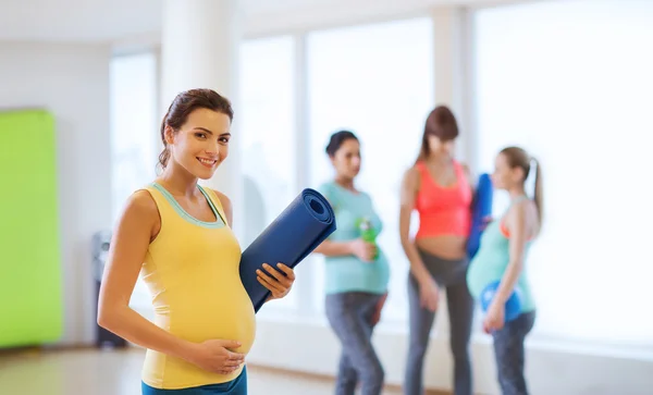 Mujer embarazada feliz con estera en el gimnasio —  Fotos de Stock