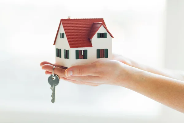 Close up of hands holding house model and keys — Stock Photo, Image