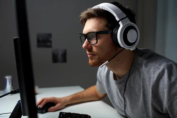 Hombre en auriculares jugando videojuego de ordenador en casa —  Fotos de Stock