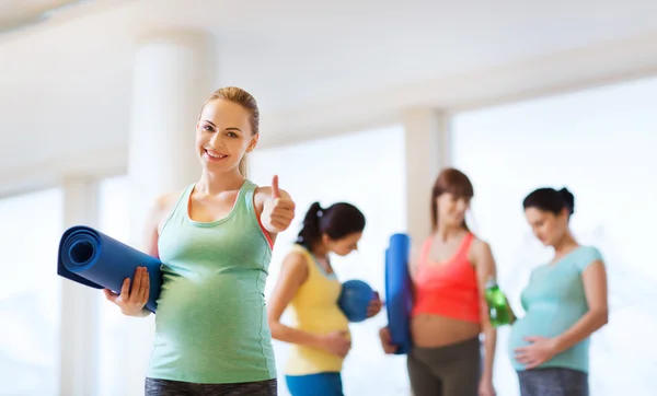 Gravid kvinna med matta i gymmet visar tummen — Stockfoto