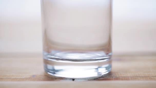 Milch fließt ins leere Glas auf Holztisch — Stockvideo