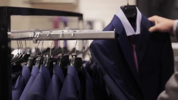 Ung man väljer kläder i klädaffär — Stockvideo
