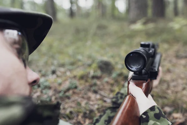 Close up of soldier or hunter with gun in forest — Stock Photo, Image