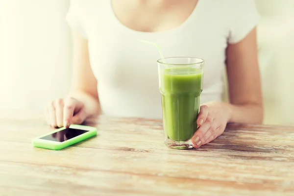 Close up of woman with smartphone and green juice — Stock Photo, Image