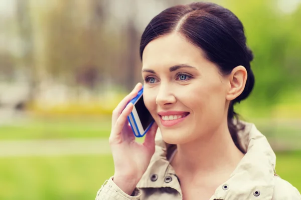 Lächelnde Frau ruft im Park mit Smartphone an — Stockfoto