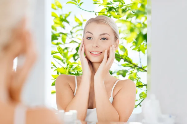 Gelukkig jonge vrouw op zoek naar de spiegel op de badkamer — Stockfoto