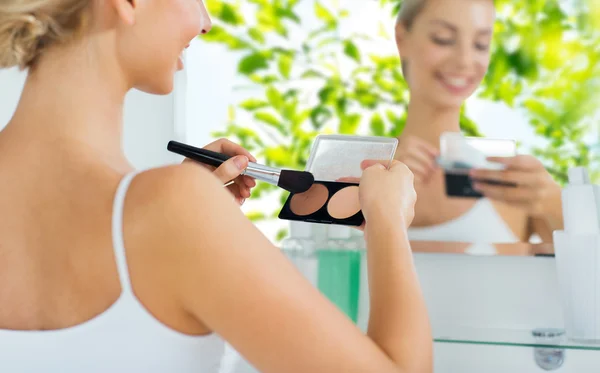Kvinna med makeup borste och foundation på badrum — Stockfoto