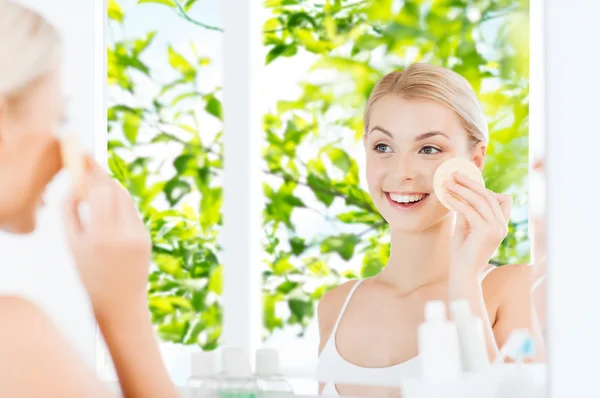 Ung kvinna Tvätta ansikte med svamp på badrum — Stockfoto