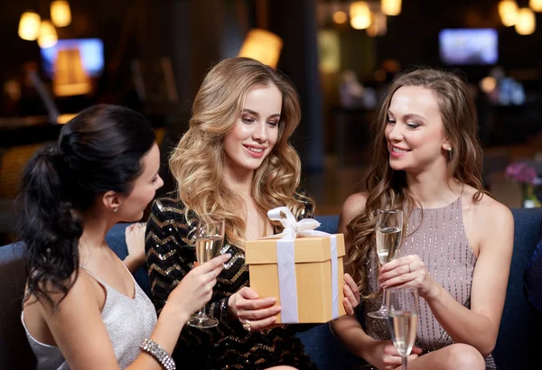 Mujeres felices con champán y regalo en el club nocturno —  Fotos de Stock