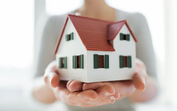 Close up de mãos segurando casa ou modelo de casa — Fotografia de Stock