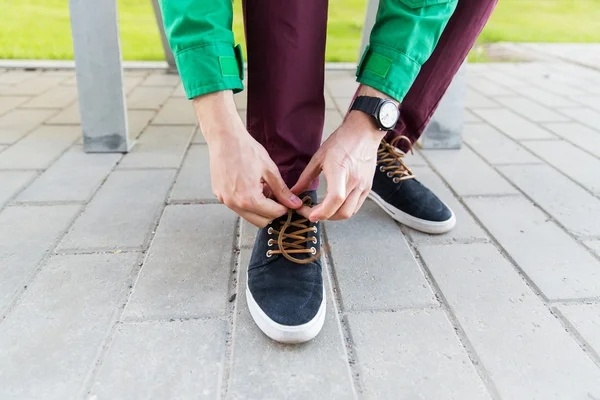 Close up of male hands tying shoe laces on street — Stock Photo, Image