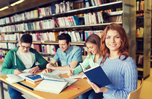 Estudantes felizes lendo livros na biblioteca — Fotografia de Stock