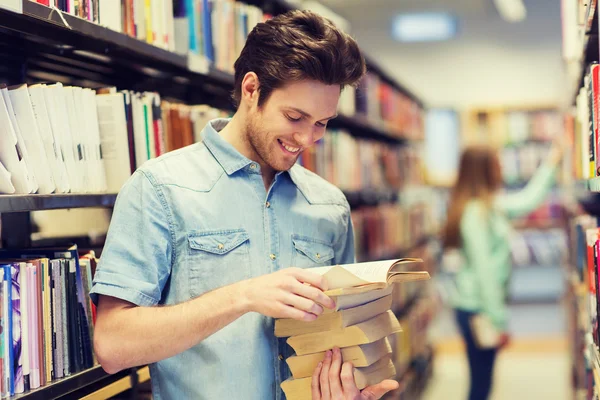 Happy student nebo muž s knihou v knihovně — Stock fotografie