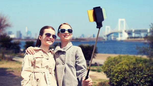 Счастливые девушки со смартфоном селфи палкой в токио — стоковое фото