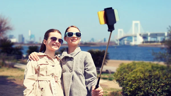 Szczęśliwy dziewcząt z smartphone selfie kij w Tokio — Zdjęcie stockowe