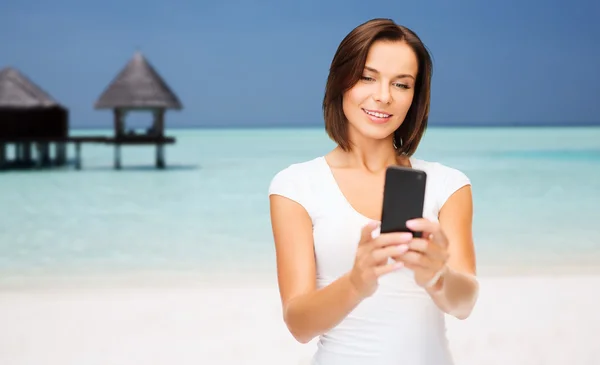 Mujer feliz tomando selfie por teléfono inteligente sobre la playa — Foto de Stock