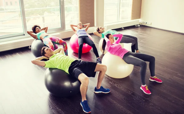 Personas felices flexionando los músculos abdominales en el fitball —  Fotos de Stock