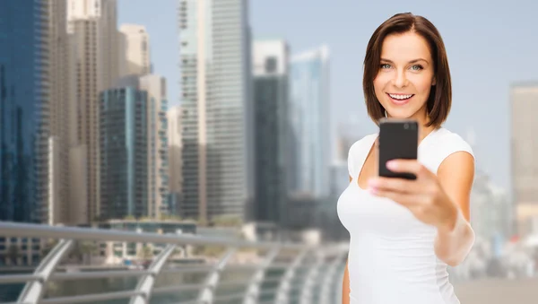 Mujer tomando foto por teléfono inteligente sobre la ciudad de dubai — Foto de Stock