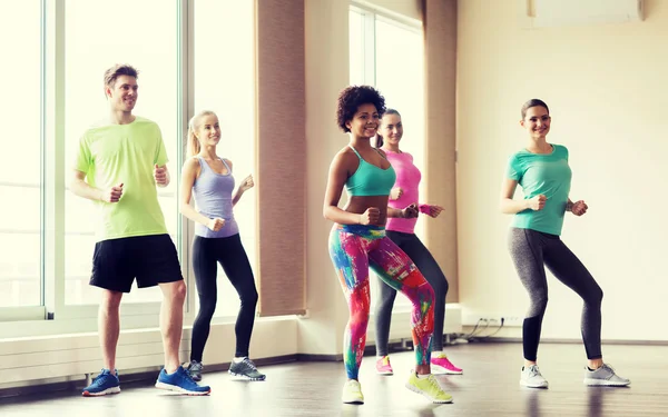 group of smiling people dancing in gym or studio