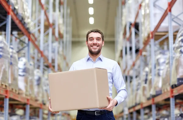 Gelukkig man met kartonnen pakje doos in het magazijn — Stockfoto