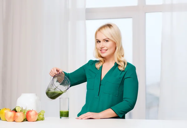 Lycklig kvinna med mixerbägaren hälla saft hemma — Stockfoto