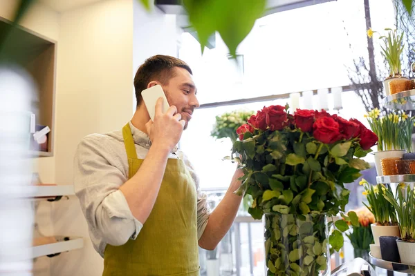 Людина зі смартфоном і червоними трояндами в квітковому магазині — стокове фото