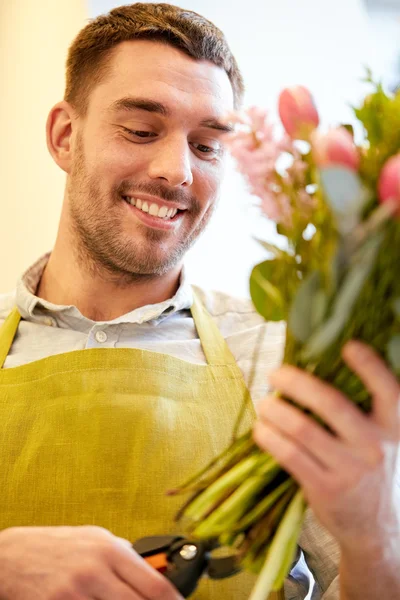Улыбающийся флорист делает букет в цветочном магазине — стоковое фото